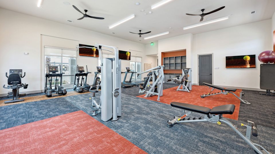 a gym room with exercise equipment and a television at The Legacy at Veramendi